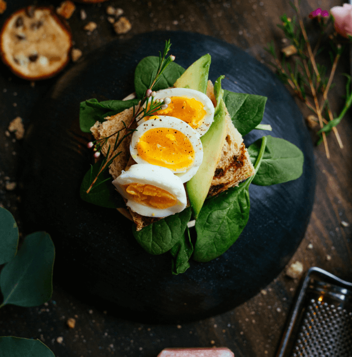 A plate of spinach with toast, avocado and egg presented as art.